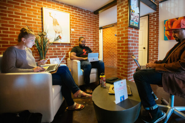 Three individuals work on computers in office lobby