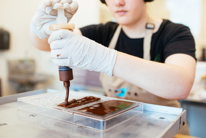 Candy maker in small business squeezes chocolate into tray