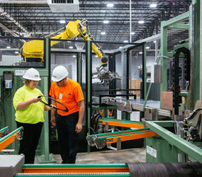 Man and woman inspect plastic ring in manufacturing setting