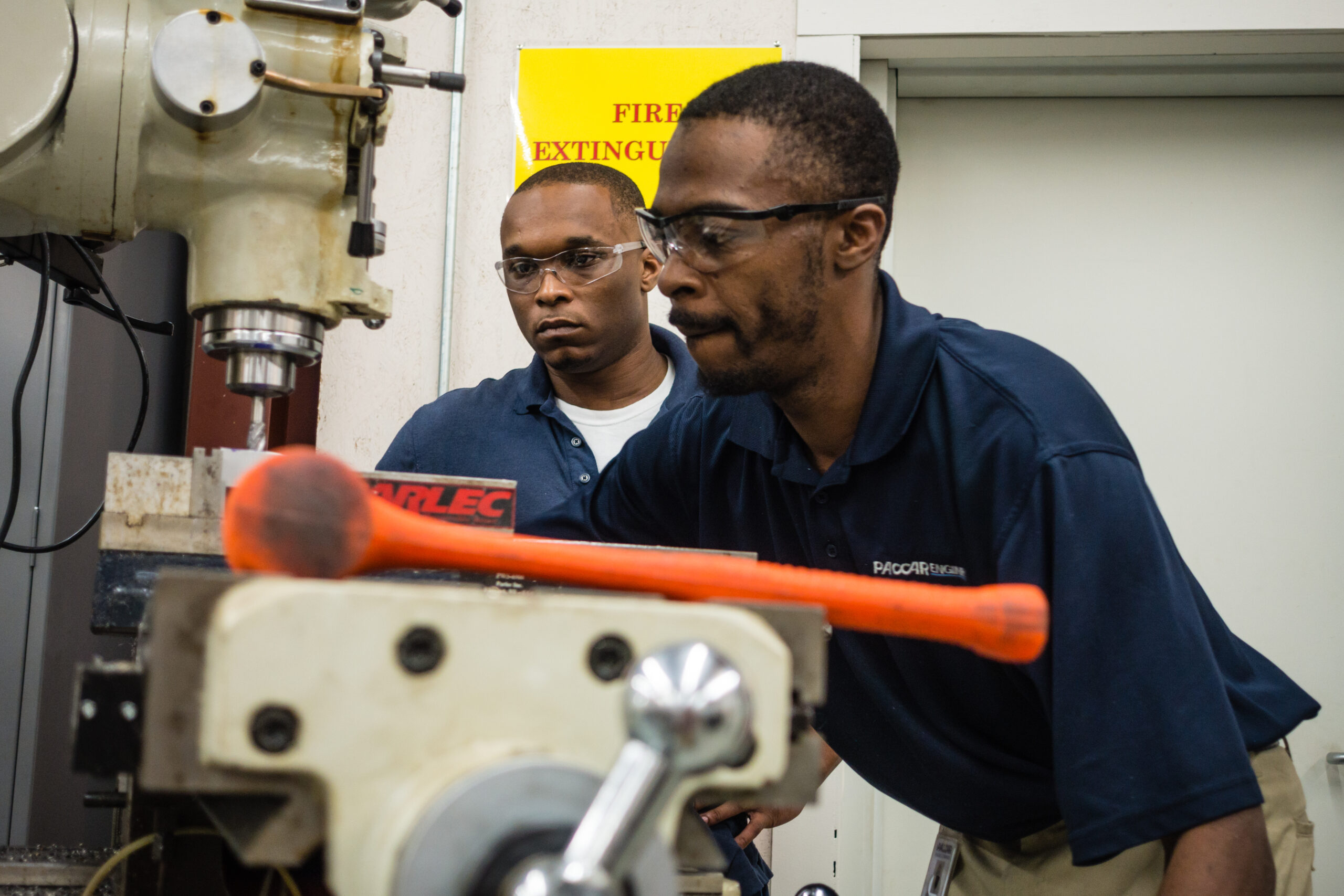 2 men in blue polos working in an industrial setting